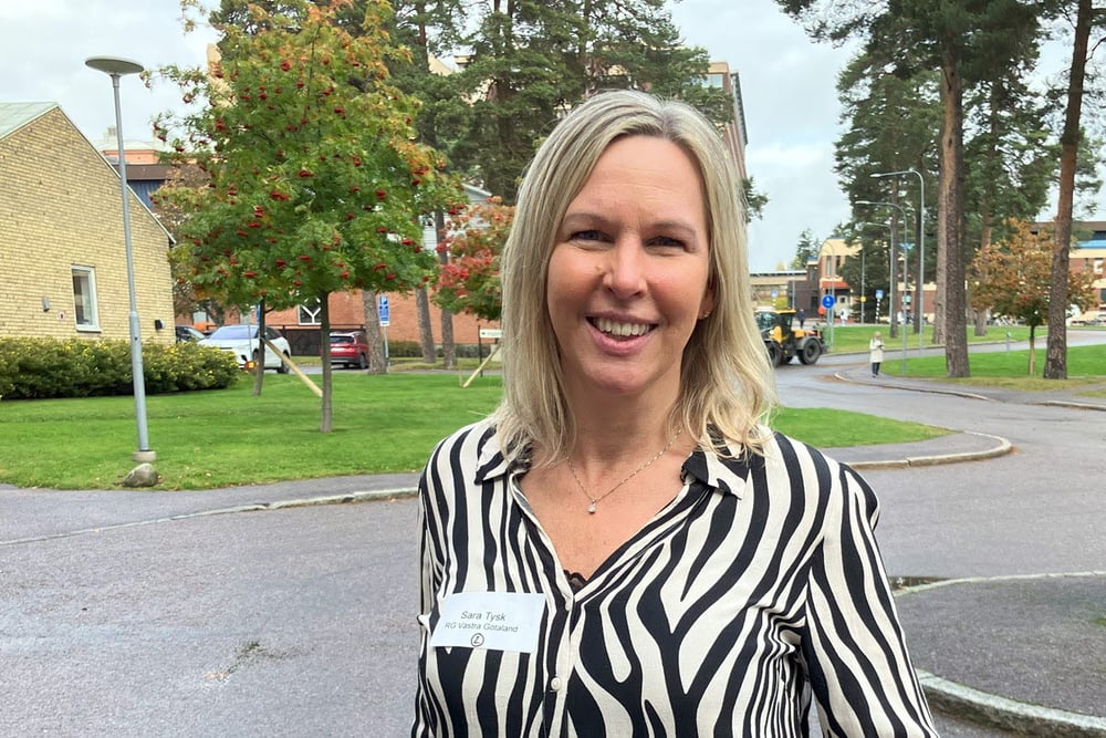 Porträtt av en person med namnbricka som visar ”Sara Tysk, RG Västra Götaland”, utomhus i en institutionsliknande miljö.