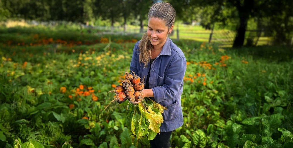 Person som står med grödor i en trädgård