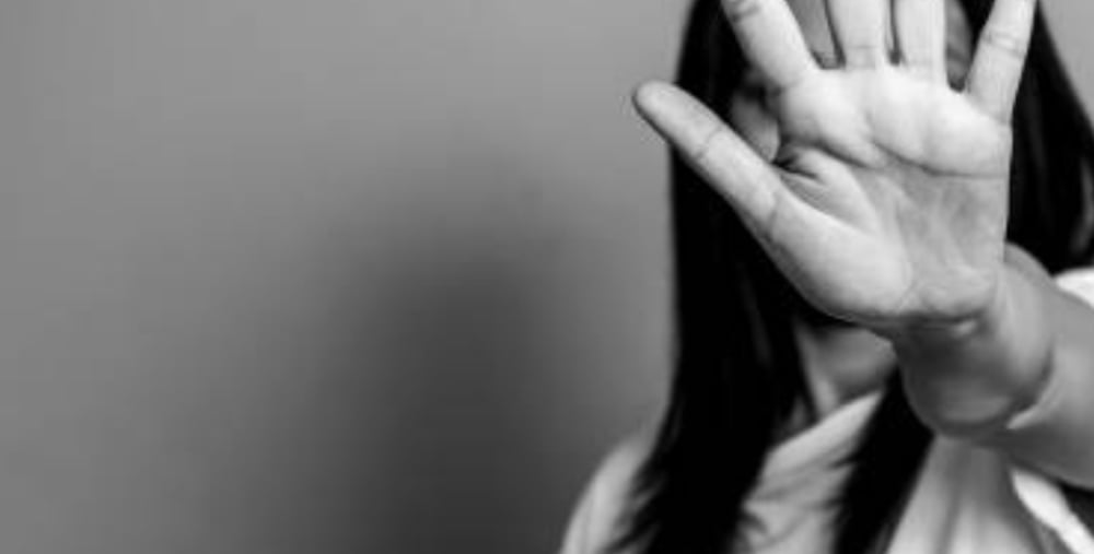 En person håller upp handen mot kameran med handflatan framåt, vilket delvis skymmer ansiktet.