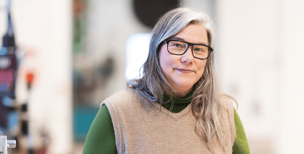 En kvinna som står i en fabrik med händerna på höfterna.
