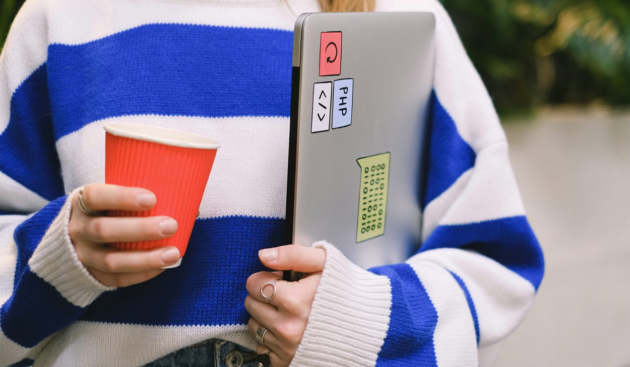 barn med randig tröja och en bärbar dator under armen.