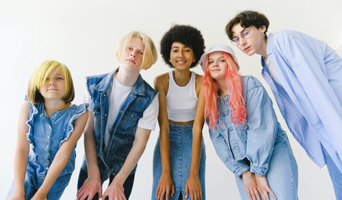 Fem personer lutar sig fram mot kameran mot en vit bakgrund.