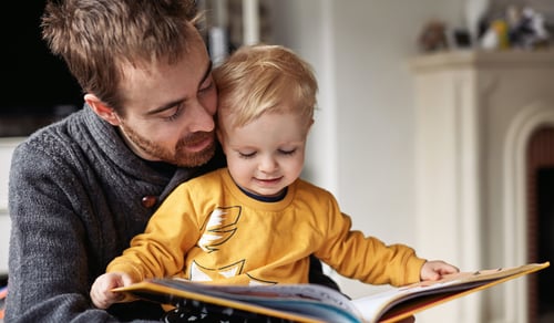 En man som läser en bok för en liten pojke.