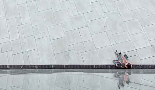 En person som sitter på en bänk framför en vägg.