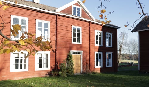 Ett rött hus med vita fönster på en solig dag.