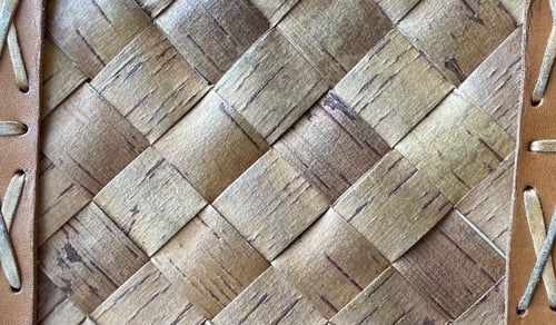 Närbild av flätat trämaterial med läderremmar.