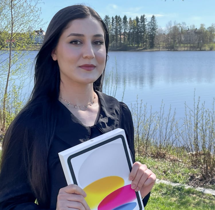 En kvinna håller upp en Ipad framför en sjö.