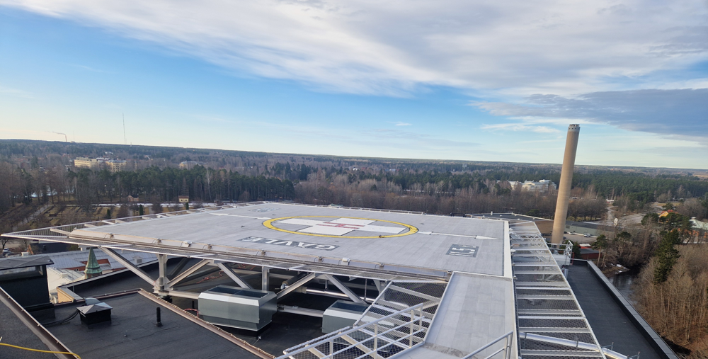 En flygbild över en helikopterflygplats med en byggnad i bakgrunden.