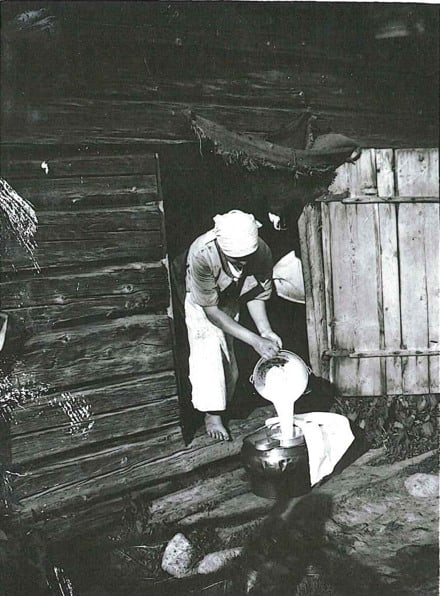 Ett svartvitt foto av en person som h&auml;ller upp mj&ouml;lk.