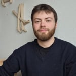 En man sitter vid ett bord med en tallrik med mat framf&ouml;r sig.