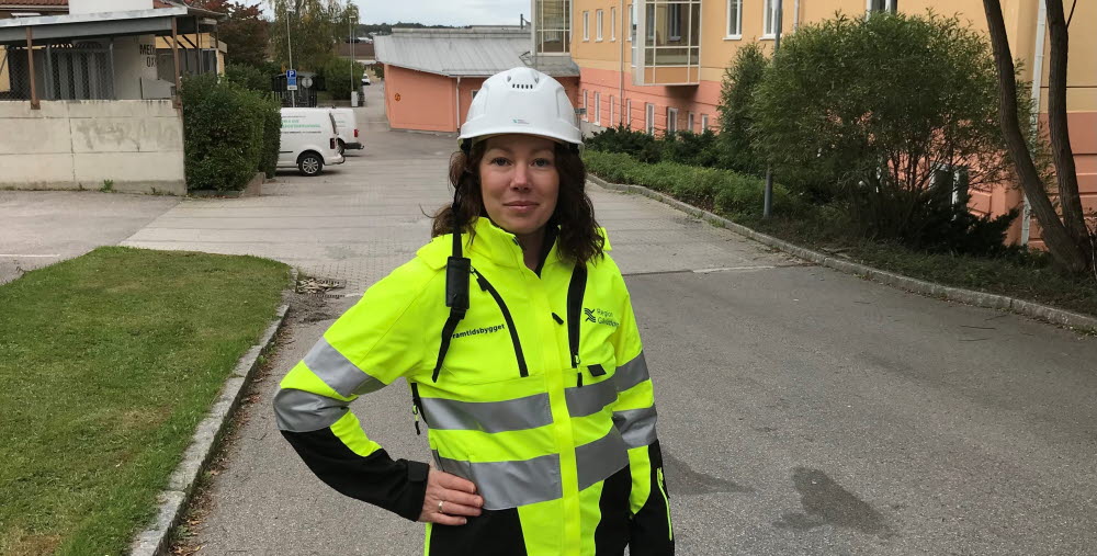Camilla Pihlqvist iklädd varseljacka och bygghjälm utanför Hudiksvalls sjukhus.