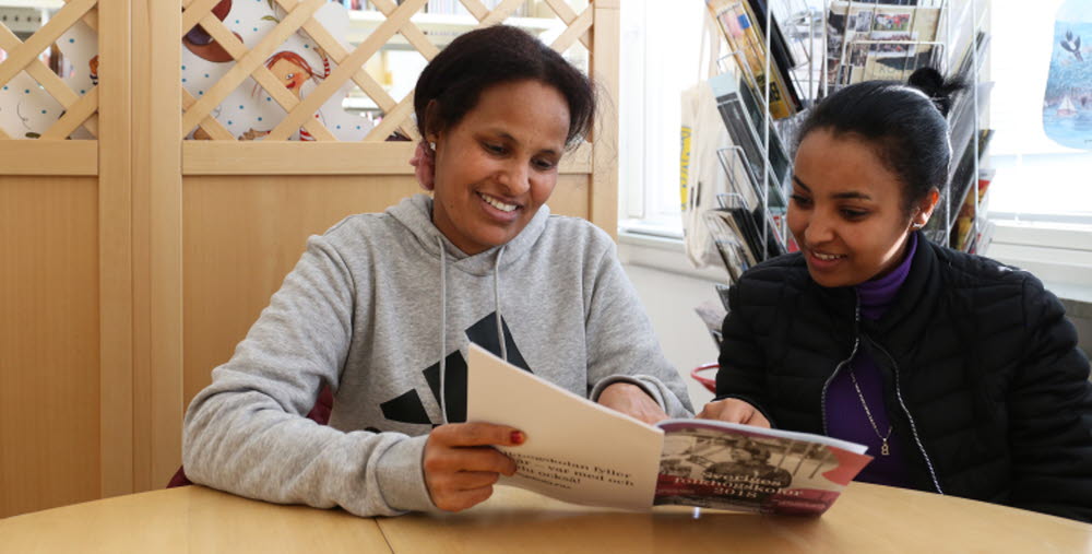Två kursdeltagare som läser bok