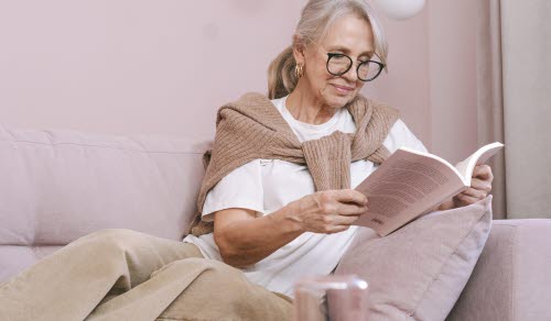 Kvinna som sitter och läser i soffa.