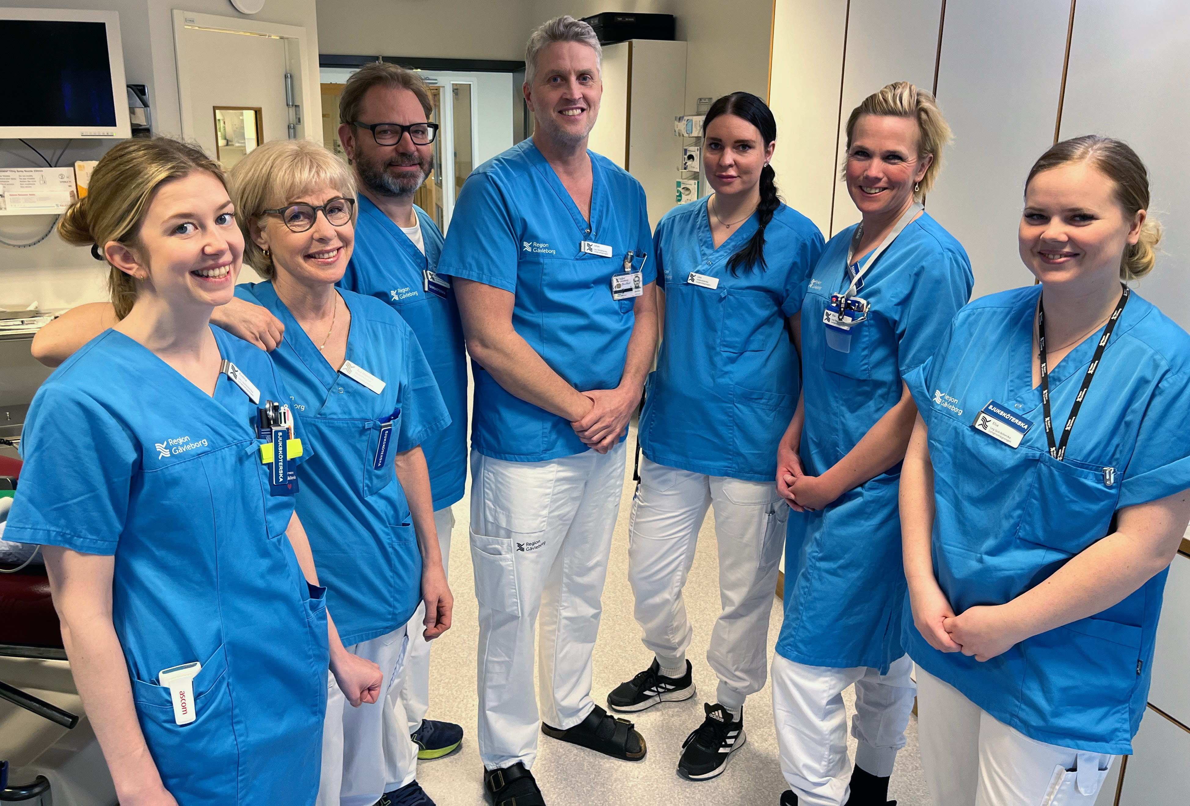 Personal på sömnapnémottagningen på Gävle sjukhus står tillsammans och tittar in i kameran. De bär blå skjorta och vita byxor och står och tittar in i kameran. 