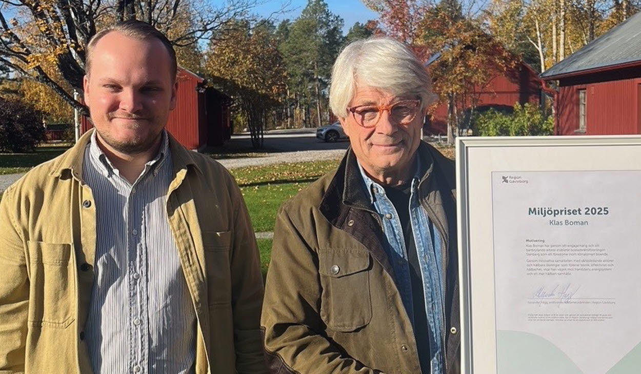 Två män står bredvid varandra i utomhusmiljö på hösten. Den ena håller i ett inramat diplom för Miljöpriset 2025.