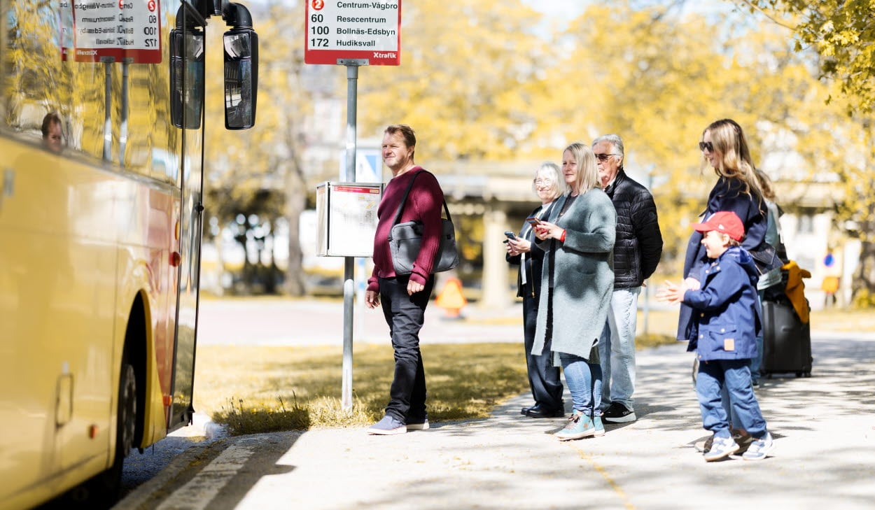 Människor som står vid en busshållplats ska kliva på en X-trafik buss.