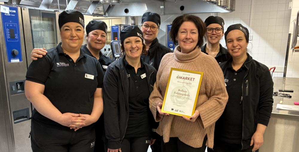 Sju personer står uppradade bredvid varandra i ett stort restaurangkök. 
