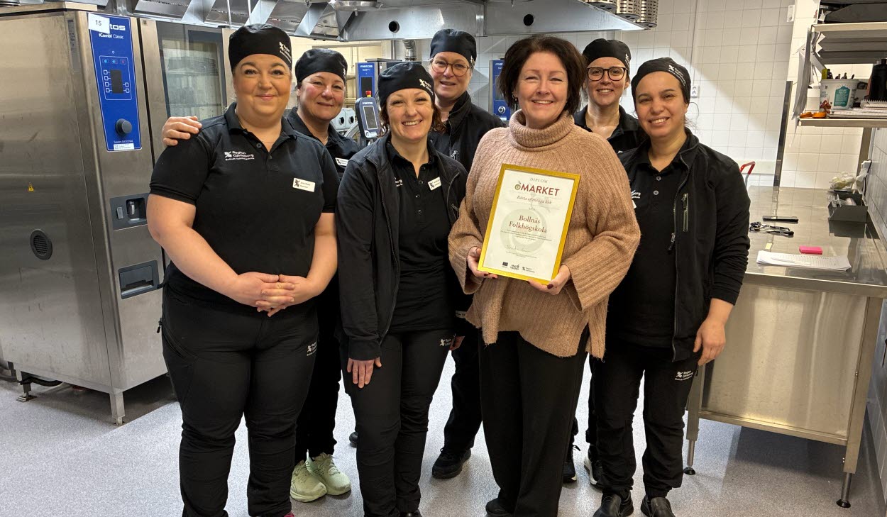 Sju personer står uppradade bredvid varandra i ett stort restaurangkök. 